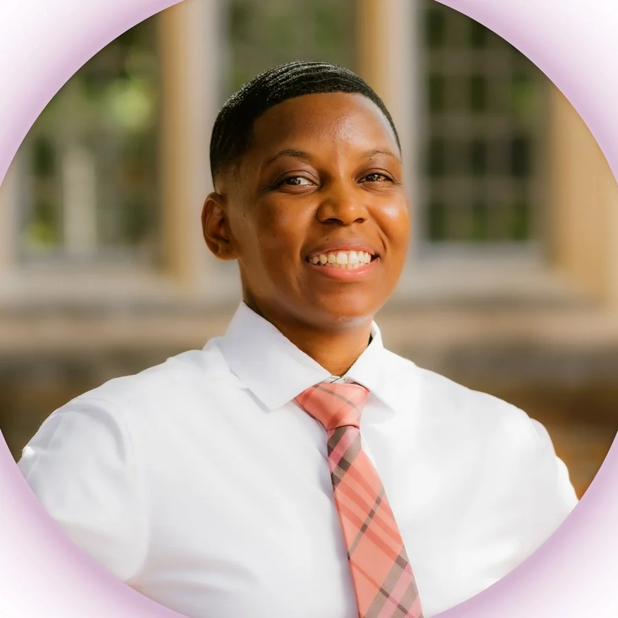 Portrait of Ja'Mesha Robinson, smiling, in a white shirt and pink plaid tie