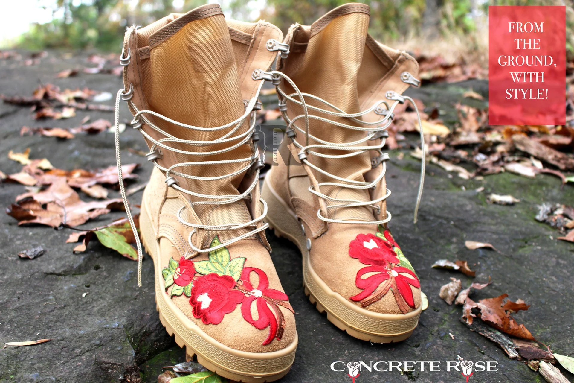 Tan military boots with red embroidered roses and ribbons on the toes, standing on a rock among autumn leaves